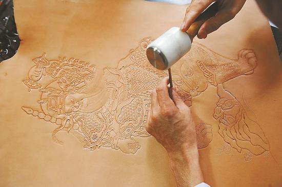 用旋转刻刀及印花工具在皮革上刻画、敲击、推拉、挤压，一幅幅深浅不一、凹凸立体的皮雕年画作品呼之欲出。